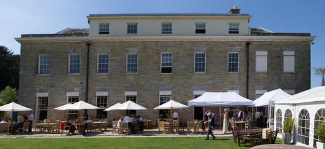 Outdoor event space at Proud Country House with charming stone building and lush lawn.