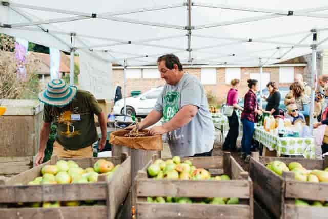 Vibrant outdoor market with fresh produce in crates at Proud Country House event.