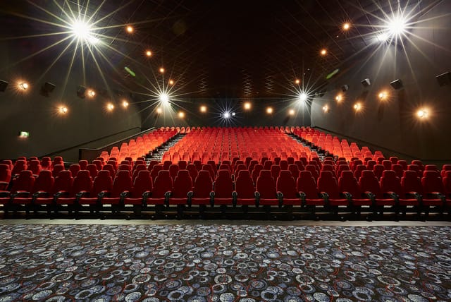 Large screen theater with red seating, ideal for corporate events and film screenings.
