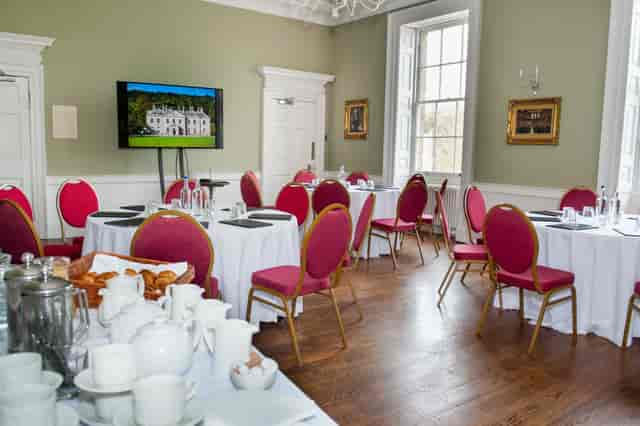 Garden marquee with round tables and pink chairs for meetings and networking events.