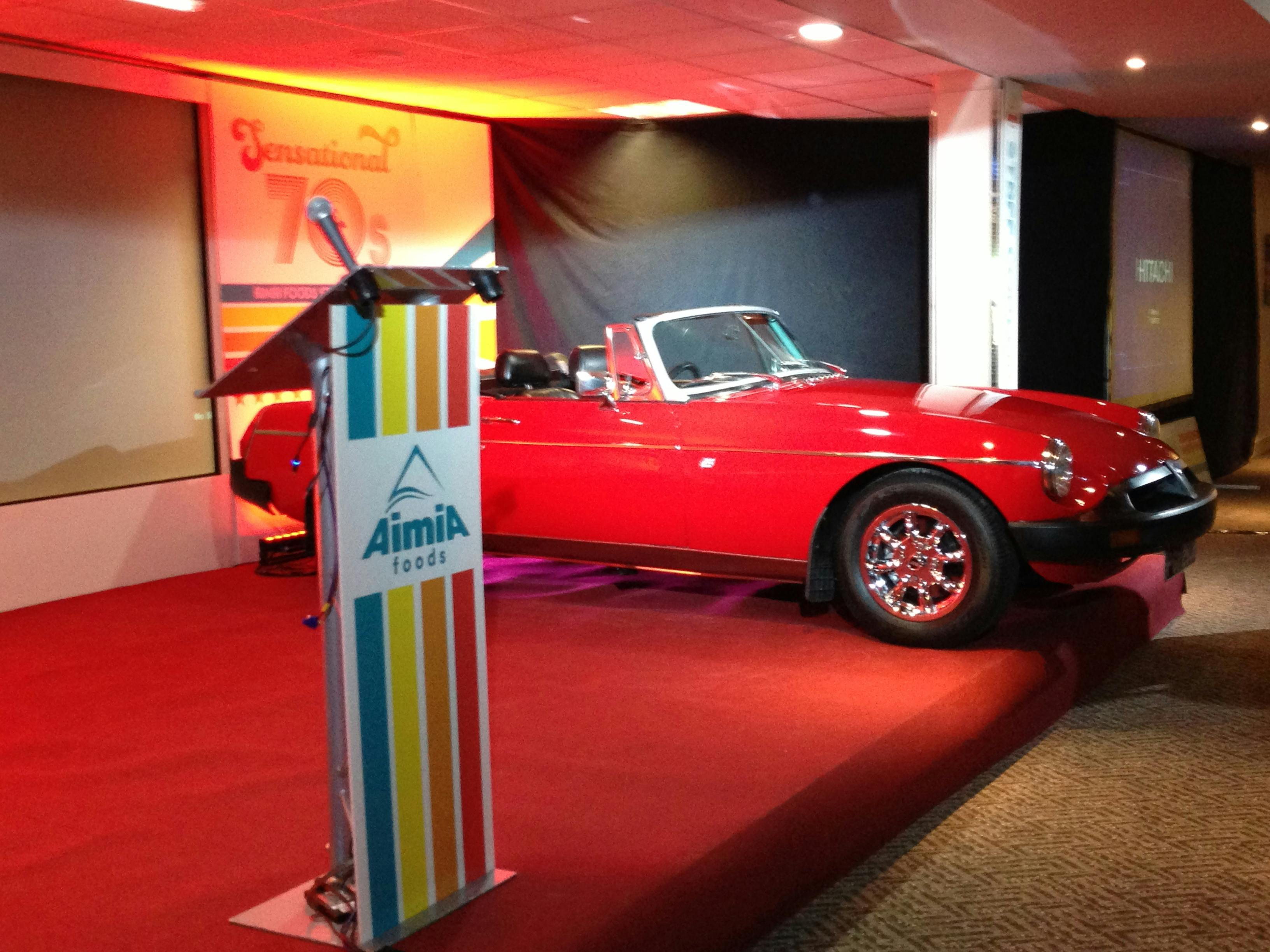 Red convertible car at DW Sports Fitness Lounge for corporate event presentation.