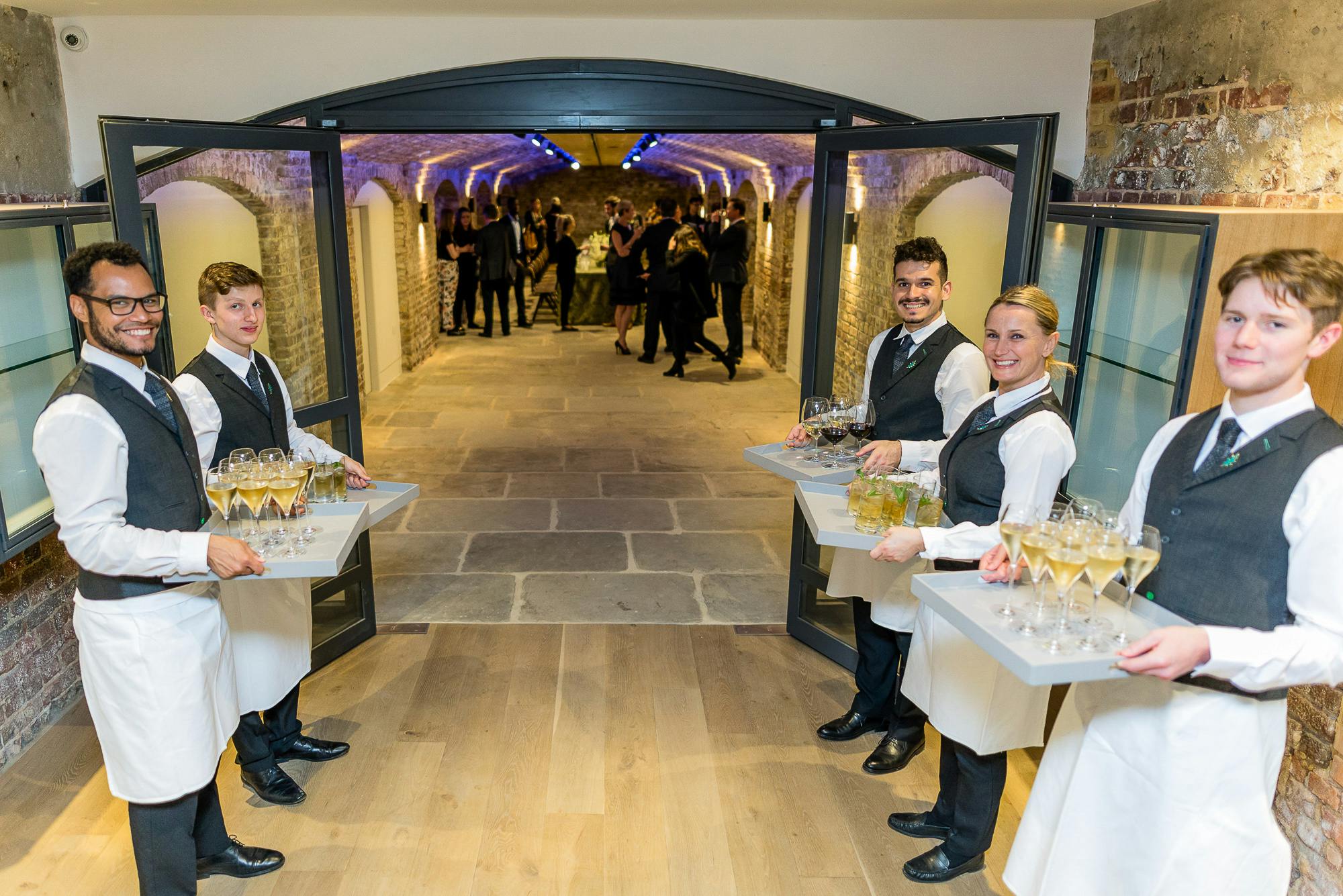 London Bridge Arches at Glaziers Hall with servers welcoming guests at an elegant event.