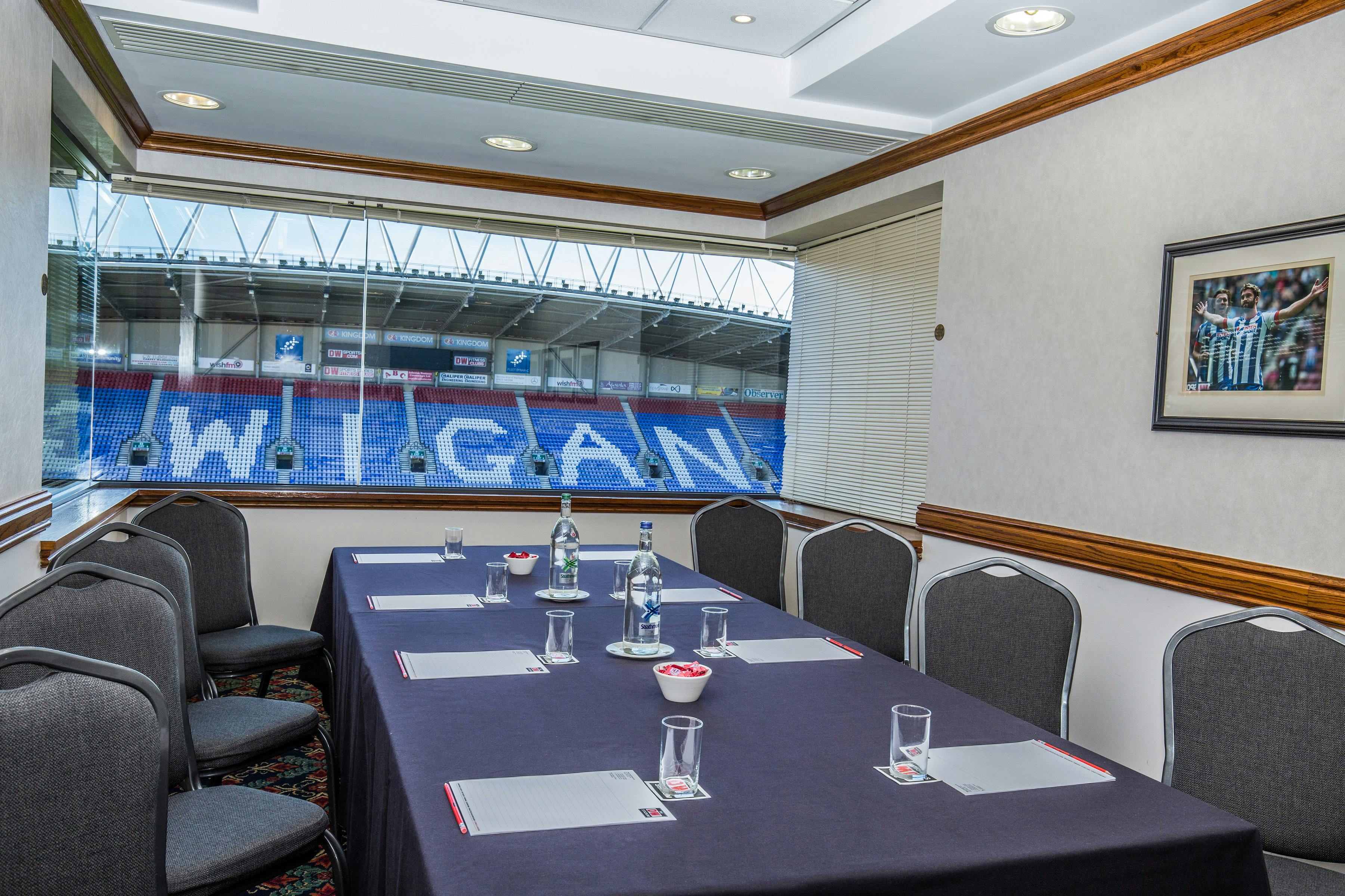 Executive meeting room with dark linen table and stadium view for corporate events.