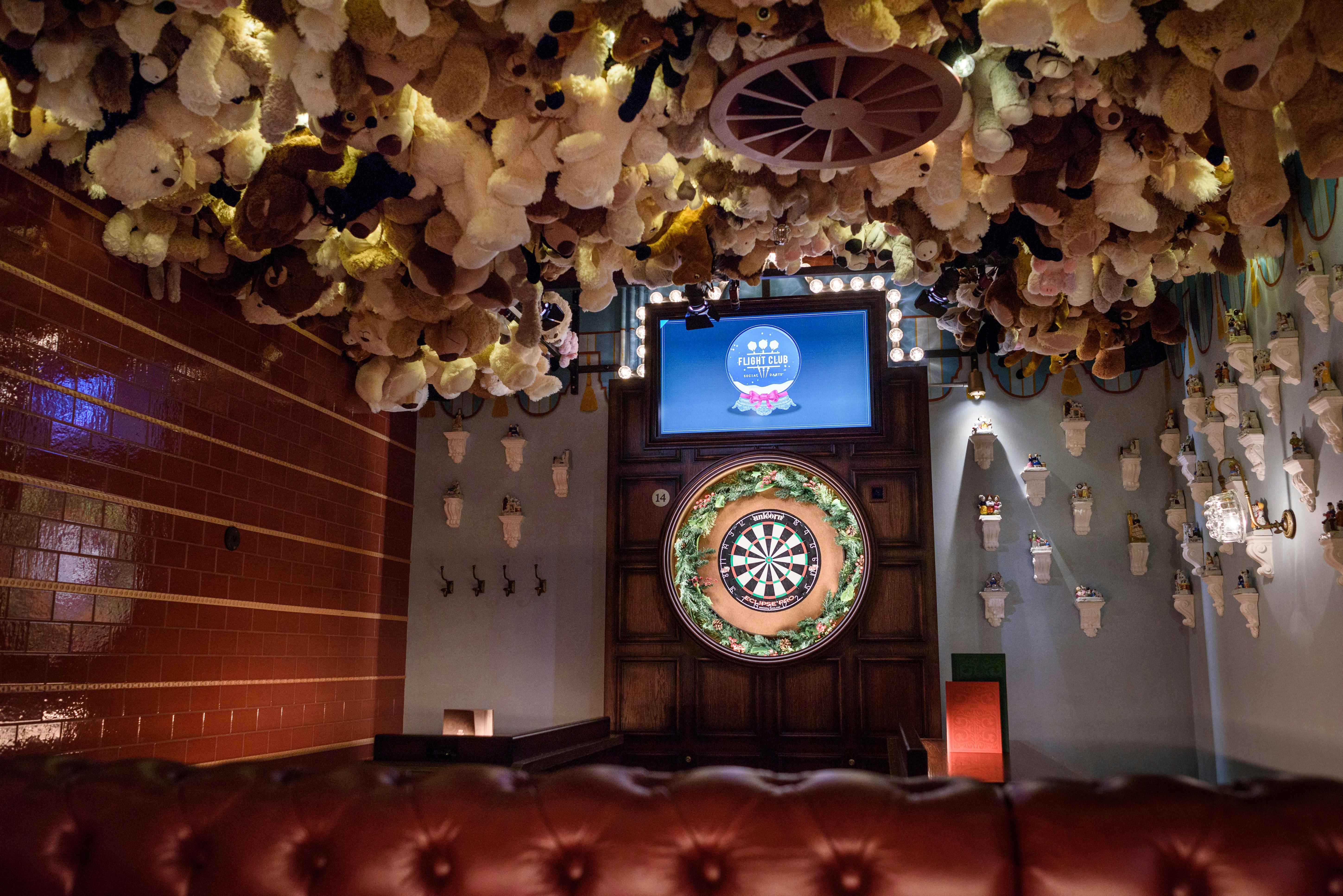 Whimsical event space with plush toy ceiling and dartboard for team-building activities.