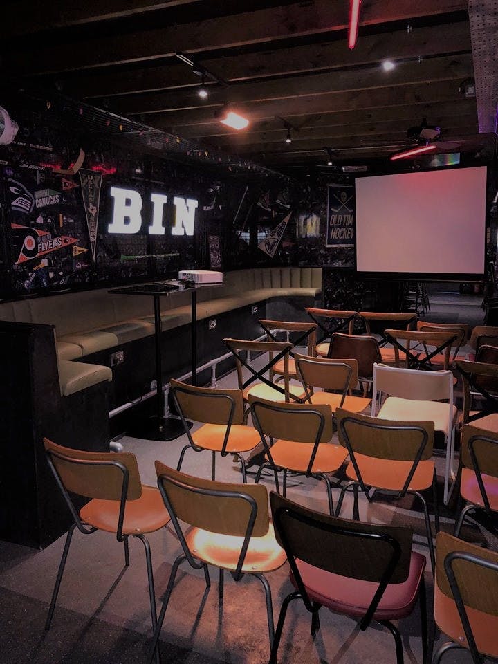 The Sin Bin event space with cozy booths and projector for gatherings in QUEENS.