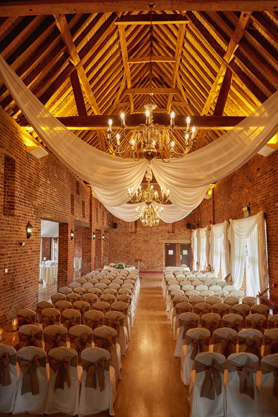 Elegant event space at The Coach House, featuring exposed brick and chandeliers for weddings.