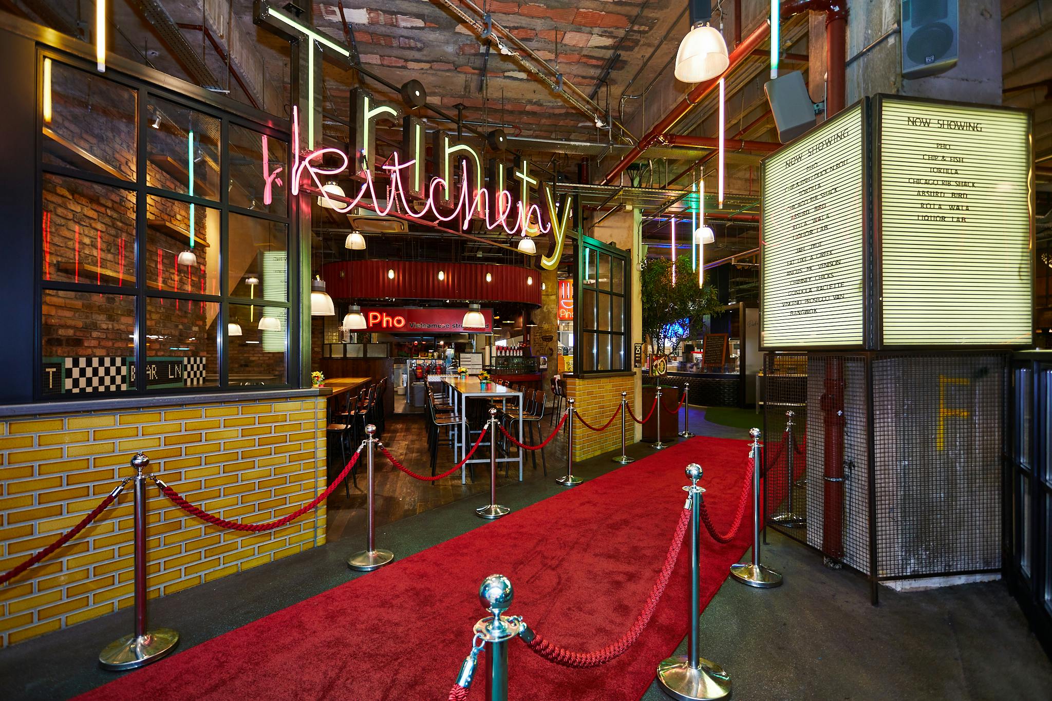 Vibrant Trinity Kitchen entrance with red carpet, perfect for events and dining experiences.