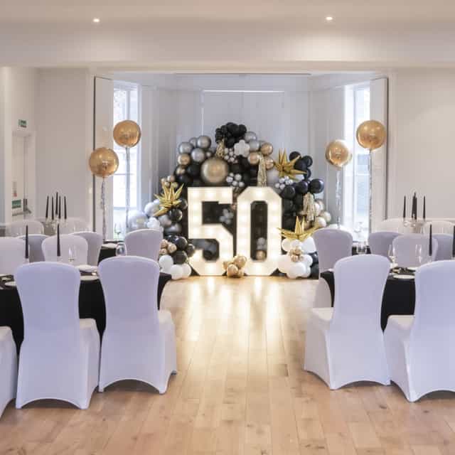 Ballroom at Linden House with elegant black, gold, and white 50th celebration setup.