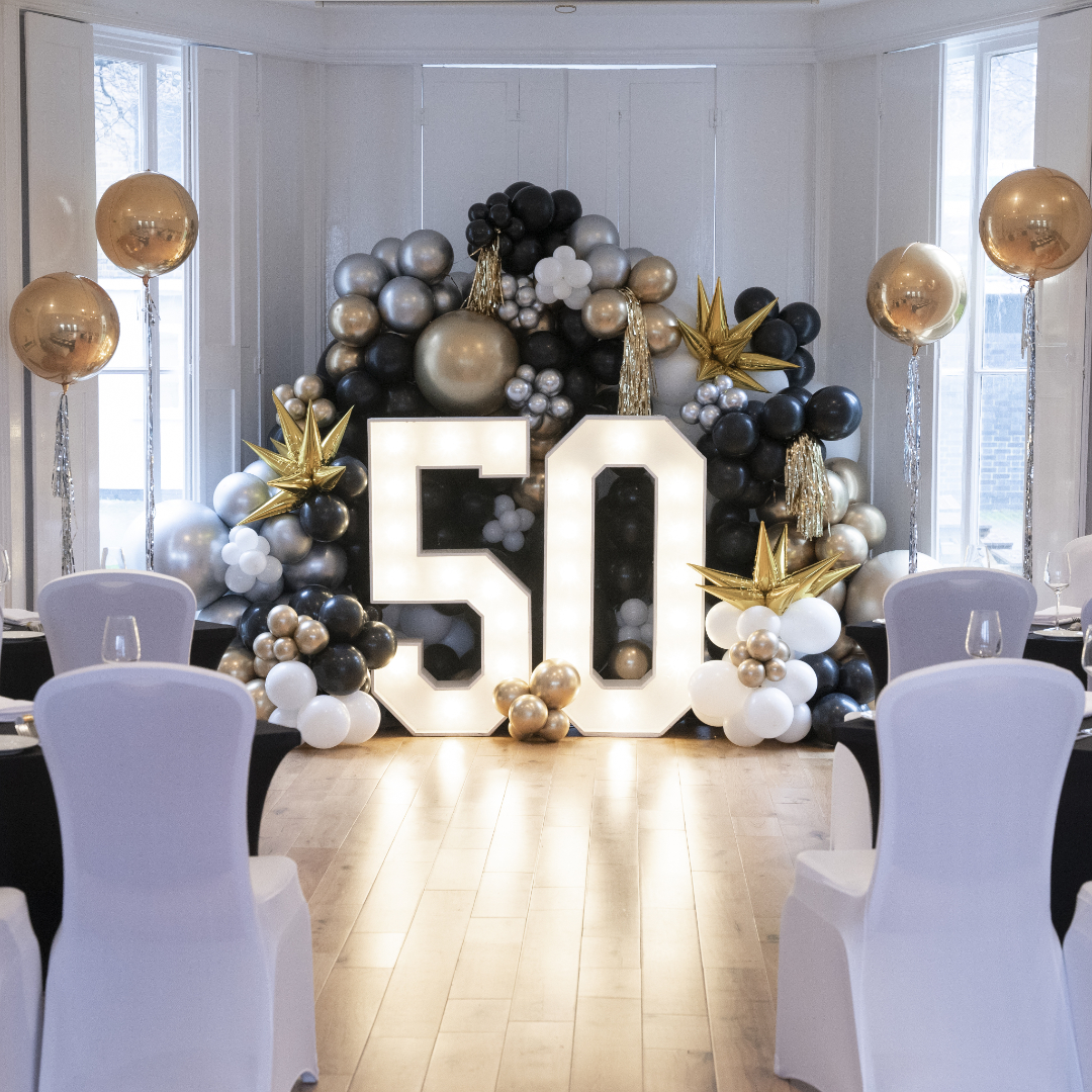 Ballroom at Linden House with elegant black, gold, and white balloon display for 50th birthday. - Banner