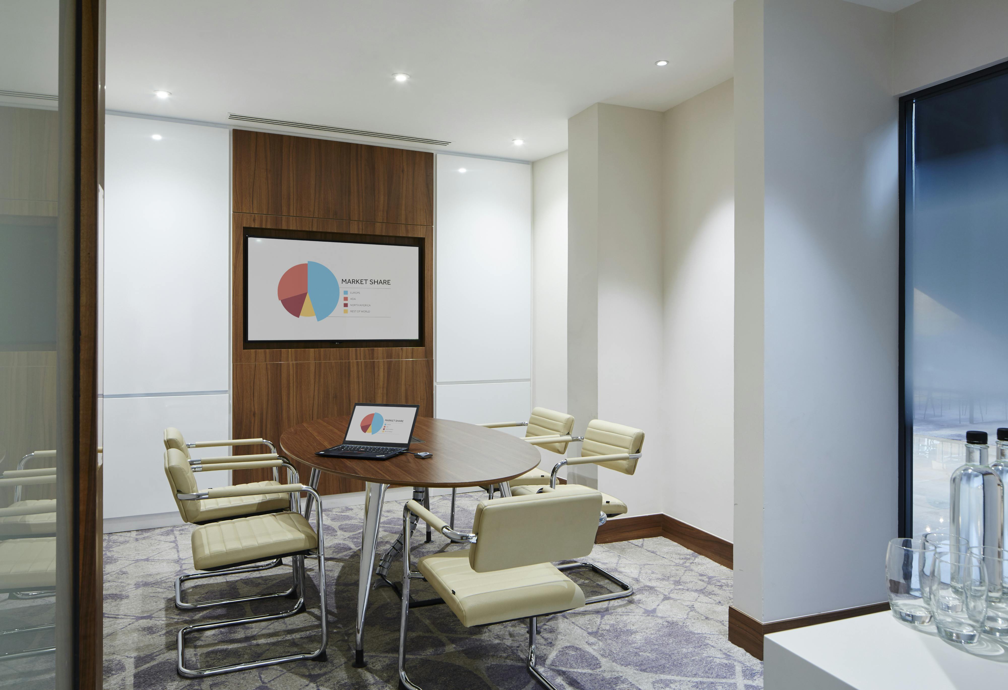 Modern meeting room with round table at London Heathrow Marriott for strategic planning.