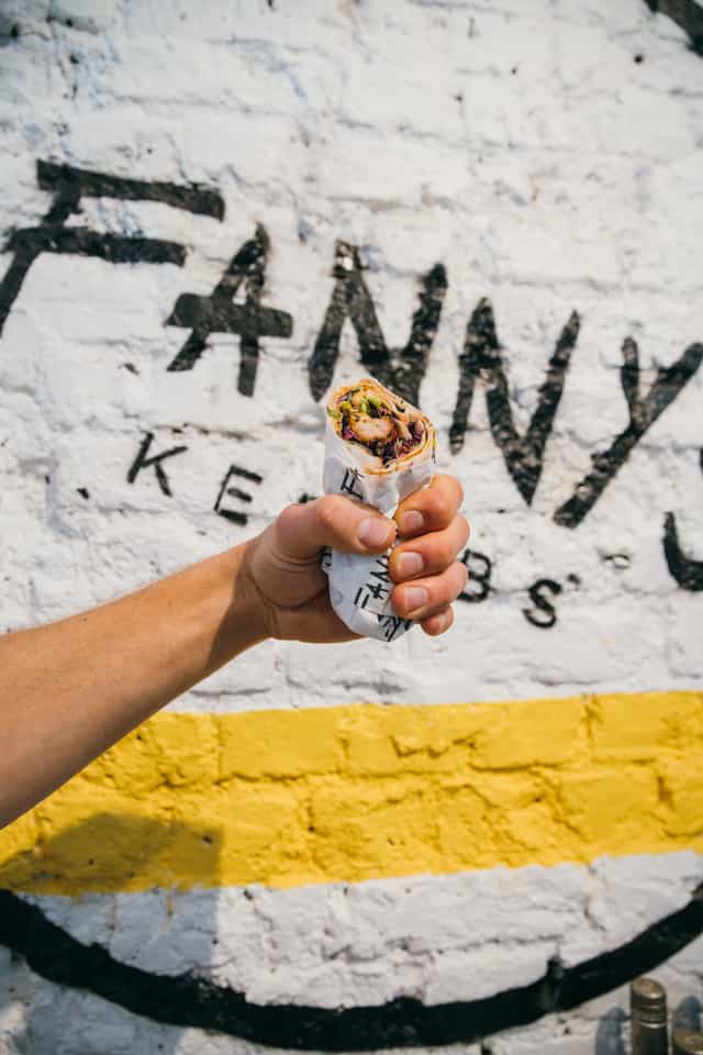 Hand holding a kebab sandwich at Fanny's Kebabs, perfect for casual dining events.