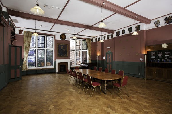 Spacious Toynbee Hall lecture room with red chairs, ideal for meetings and events.