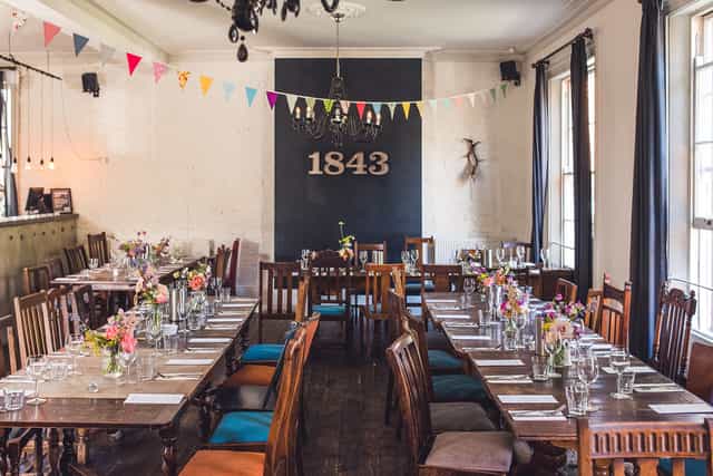 Charming event space at The Prince Albert Camden with rustic tables and floral decor.