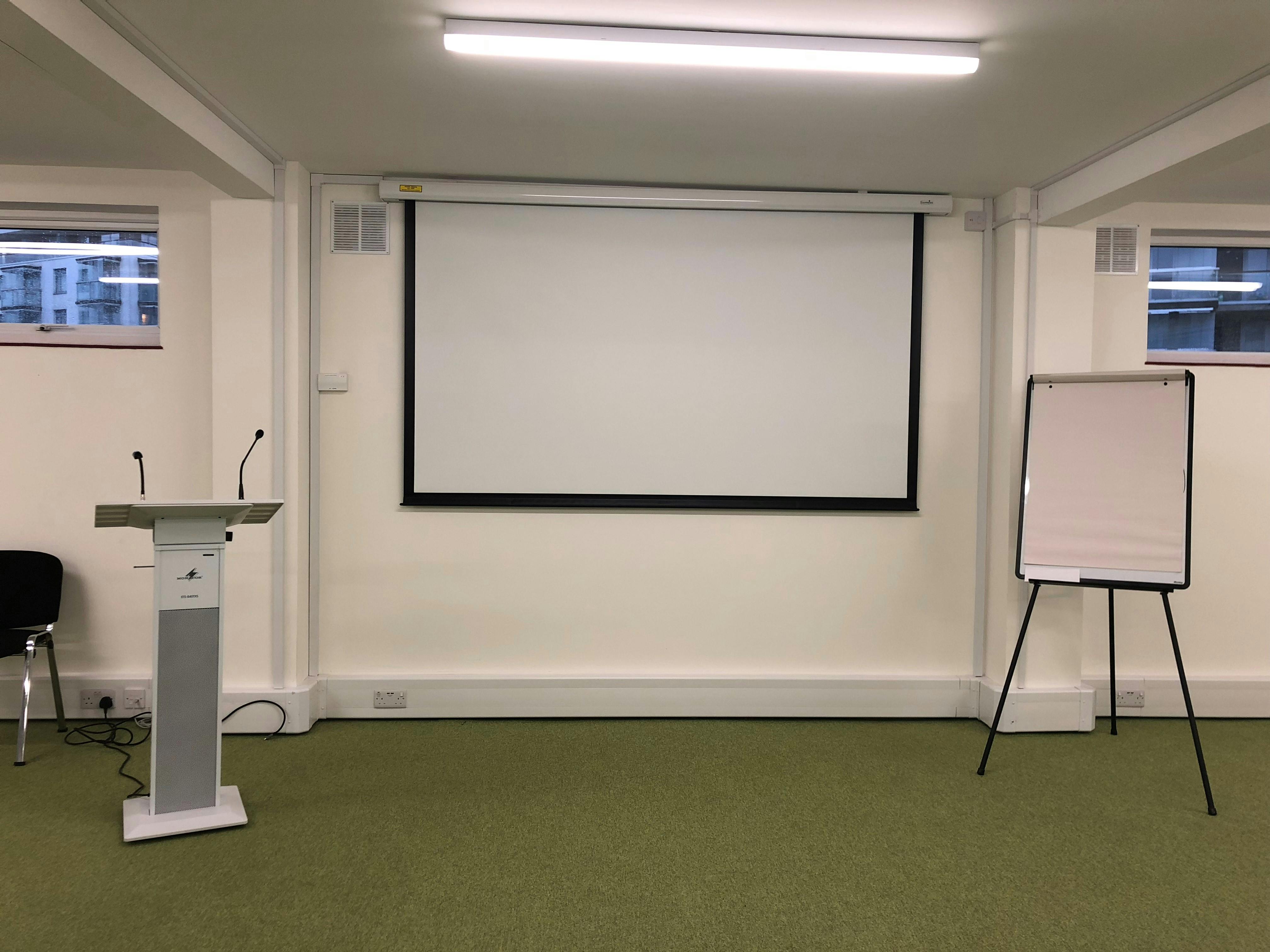 Minimalist training room with presentation screen, ideal for workshops and conferences.