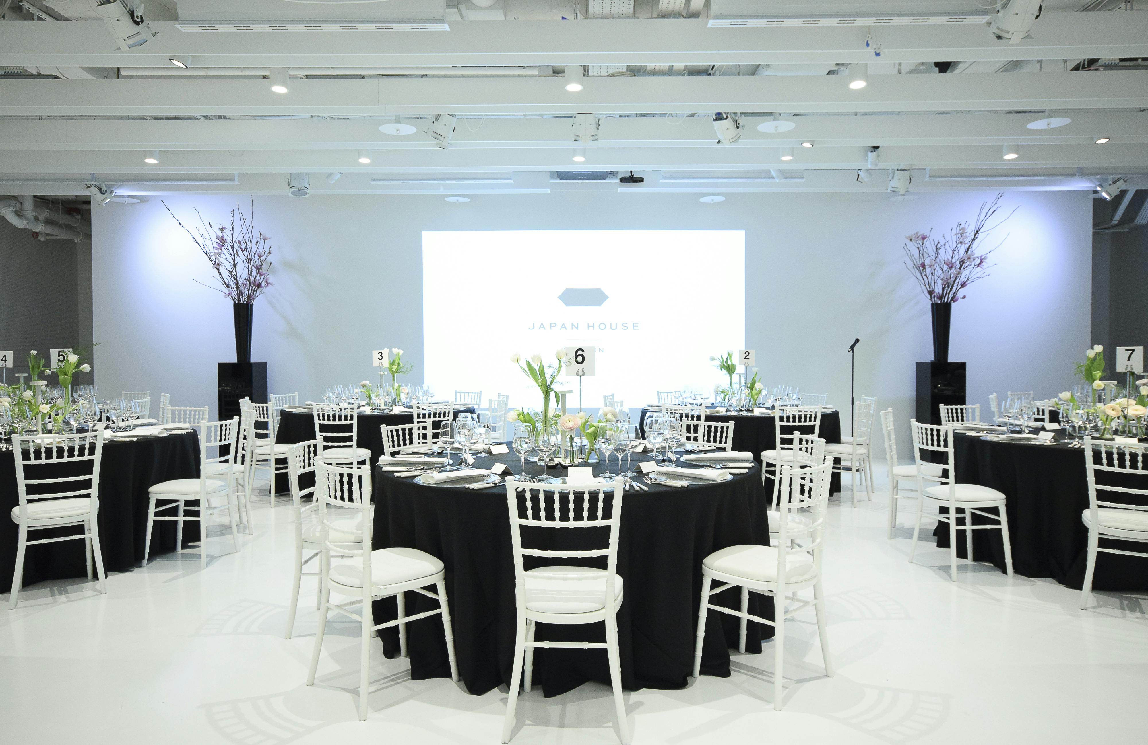 Elegant event space in Japan House with black tables and white chairs for corporate gatherings.