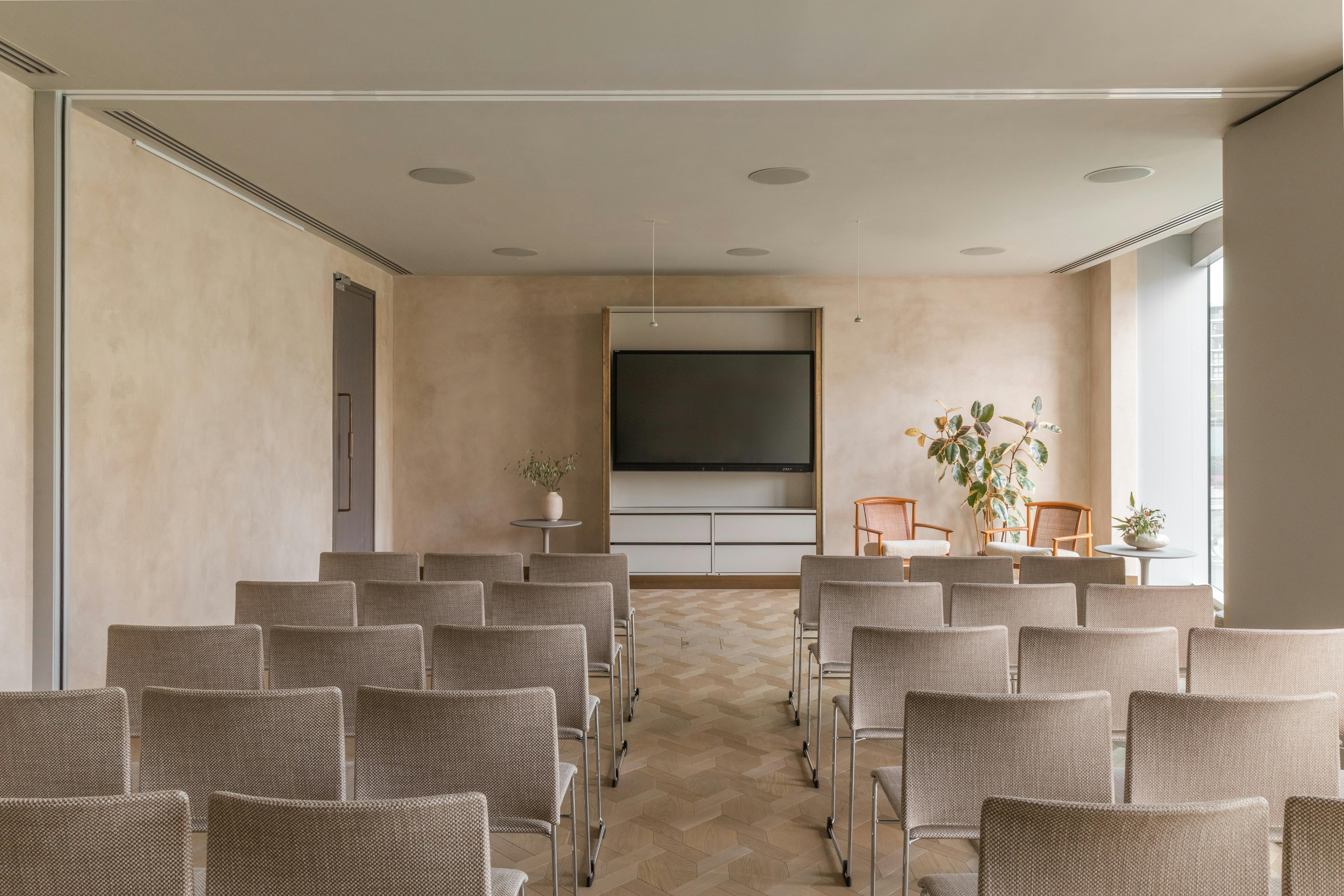 Meeting space with chairs and large screen at The Stratford, ideal for workshops and presentations.