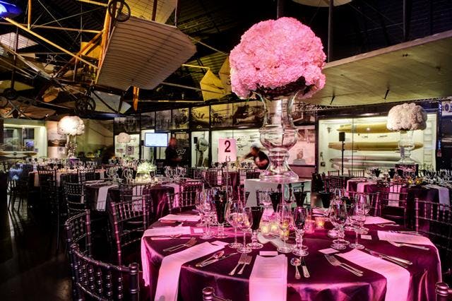 Elegant event space with floral centerpieces and vintage aircraft at The Science Museum.