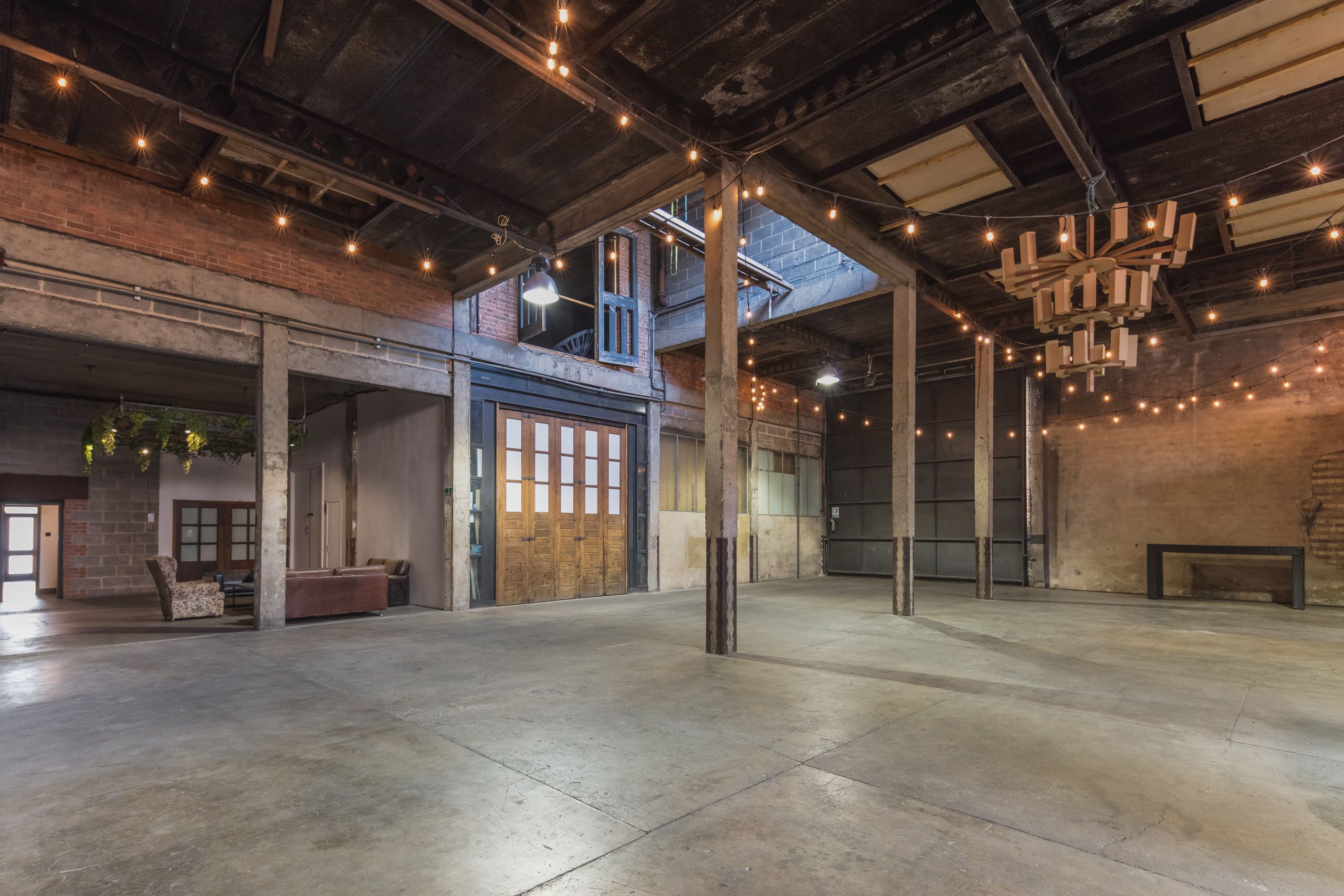 Versatile event space in Hoxton Docks with exposed brick and string lights for weddings. - Banner