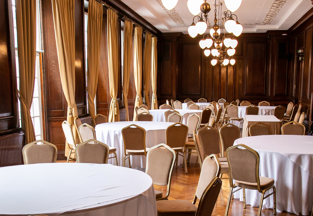 Elegant event space in Manchester Hall with round tables, ideal for conferences and banquets. - Banner