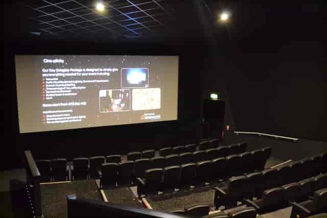 Modern event space with large screen and tiered seating for corporate meetings.
