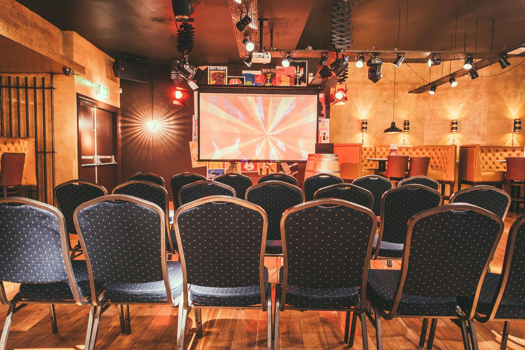 Casa De La Musica event space with chairs and screen, perfect for presentations and meetings.