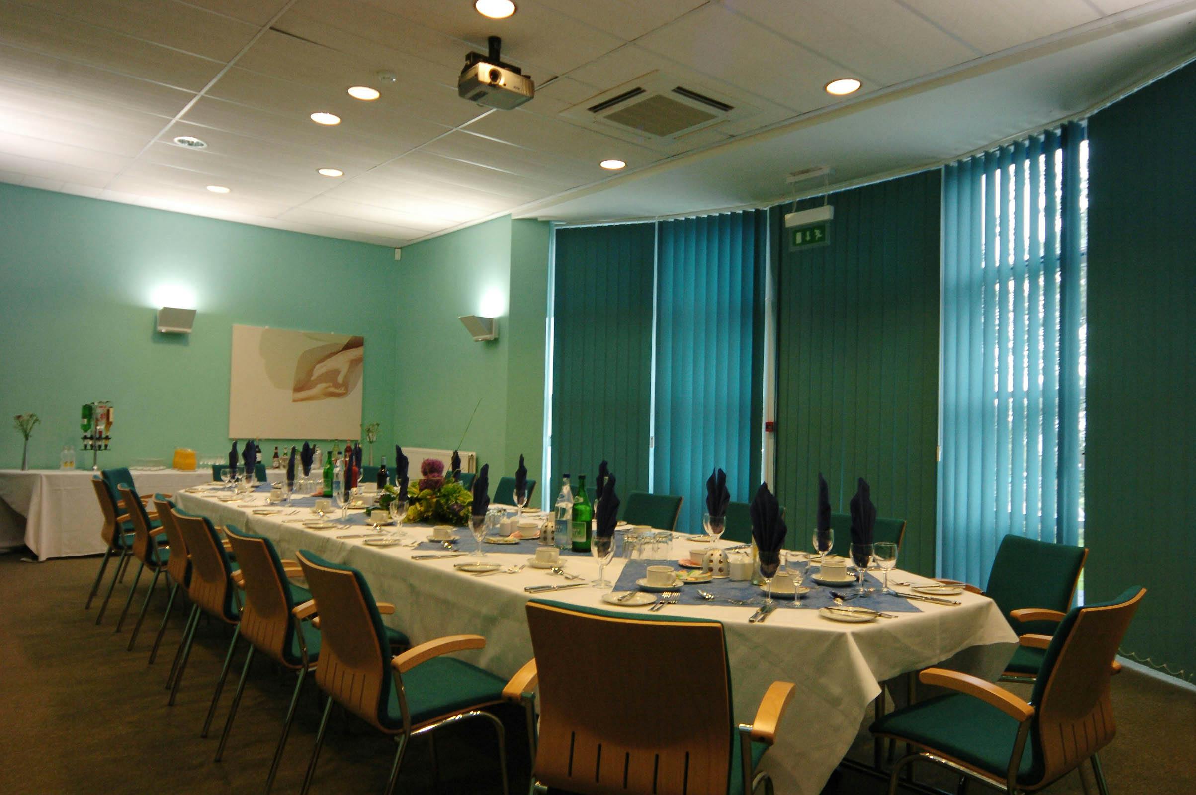 Elegant meeting room with long table set for corporate dining event in Fielder Centre.