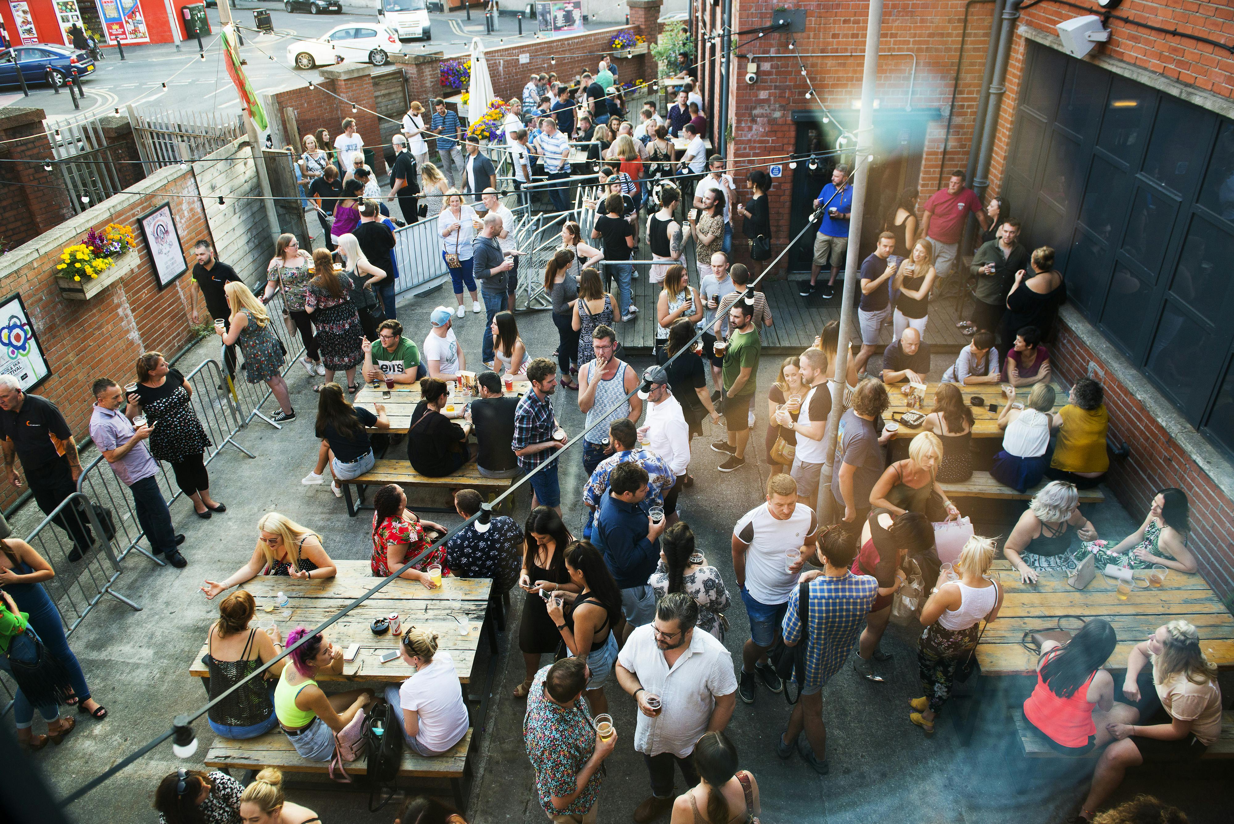 Vibrant outdoor event at Balcony Bar, Tramshed Cardiff with communal tables and lively crowd.