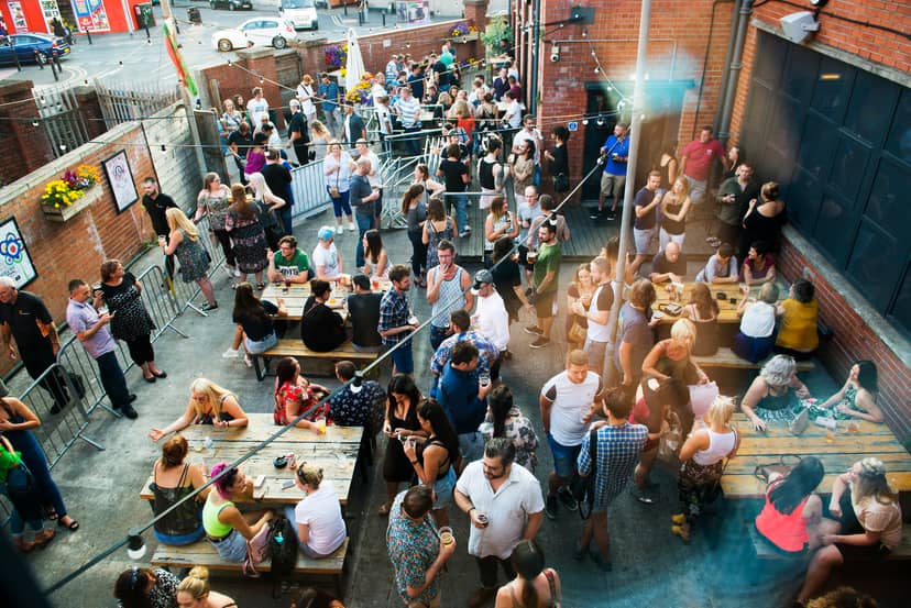 Vibrant outdoor event at Balcony Bar, Tramshed Cardiff with communal tables and lively crowd.