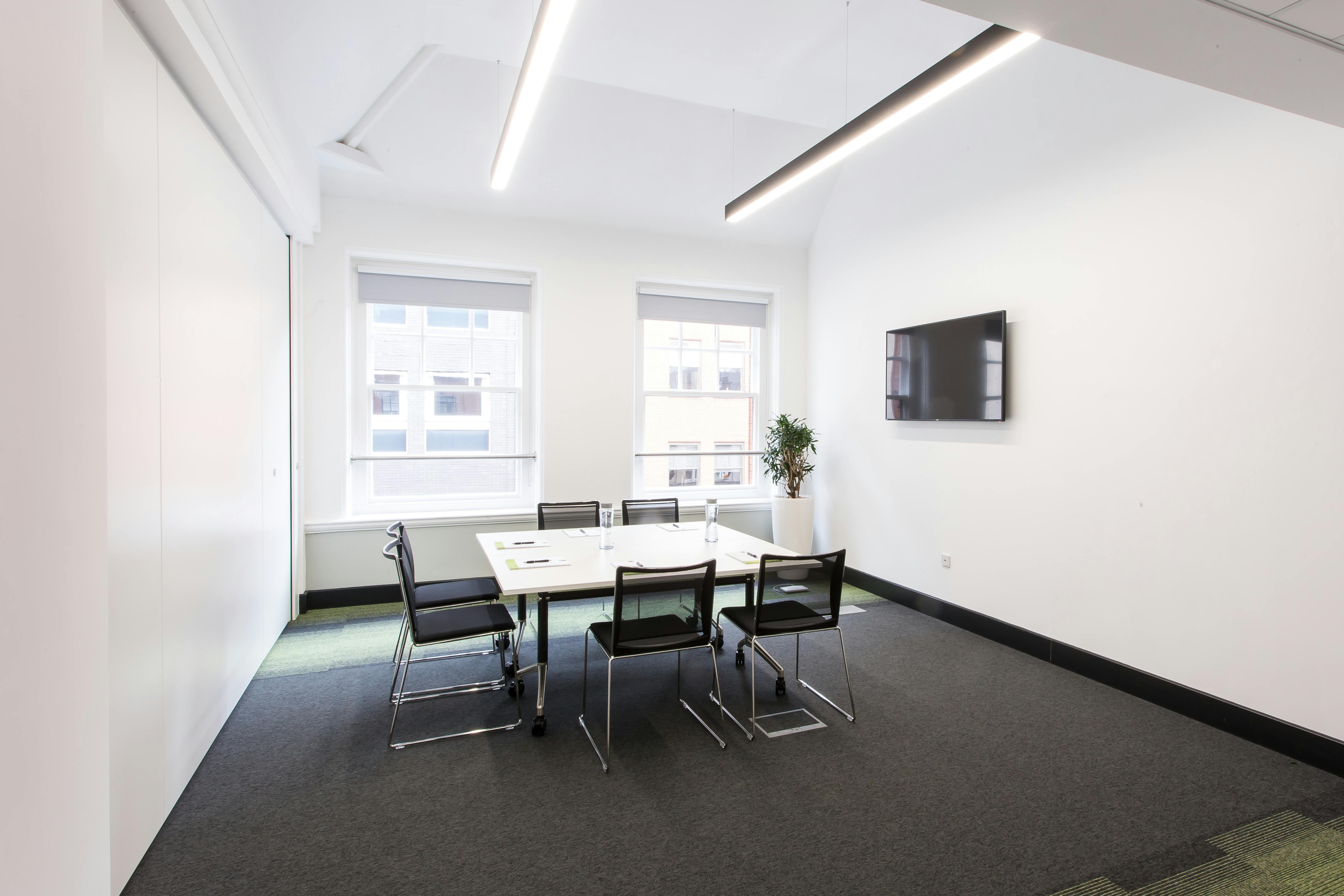 Modern meeting room with large windows, ideal for hybrid events and presentations.