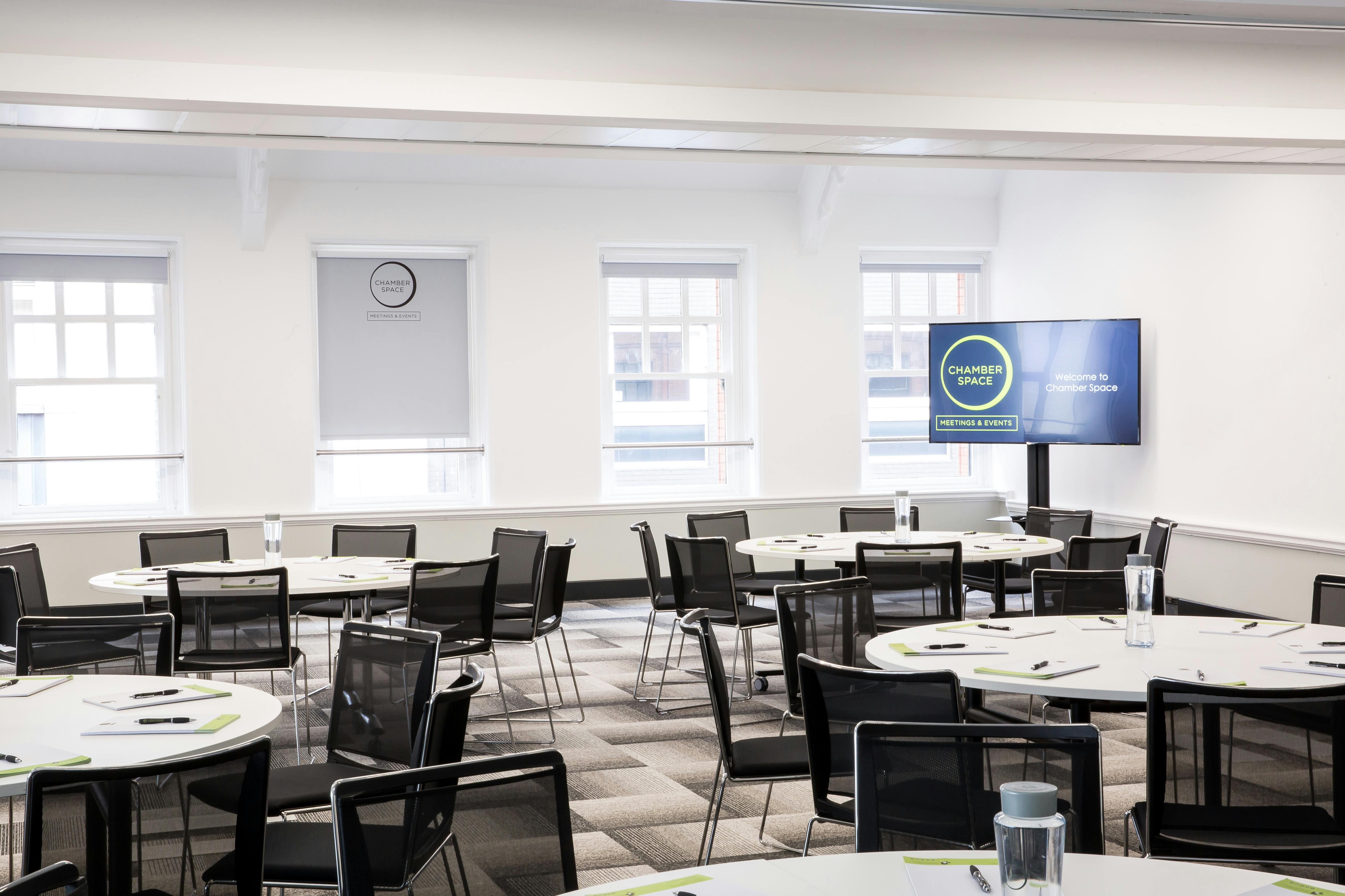 Elliot Suite meeting space with round tables and modern AV for collaboration events.