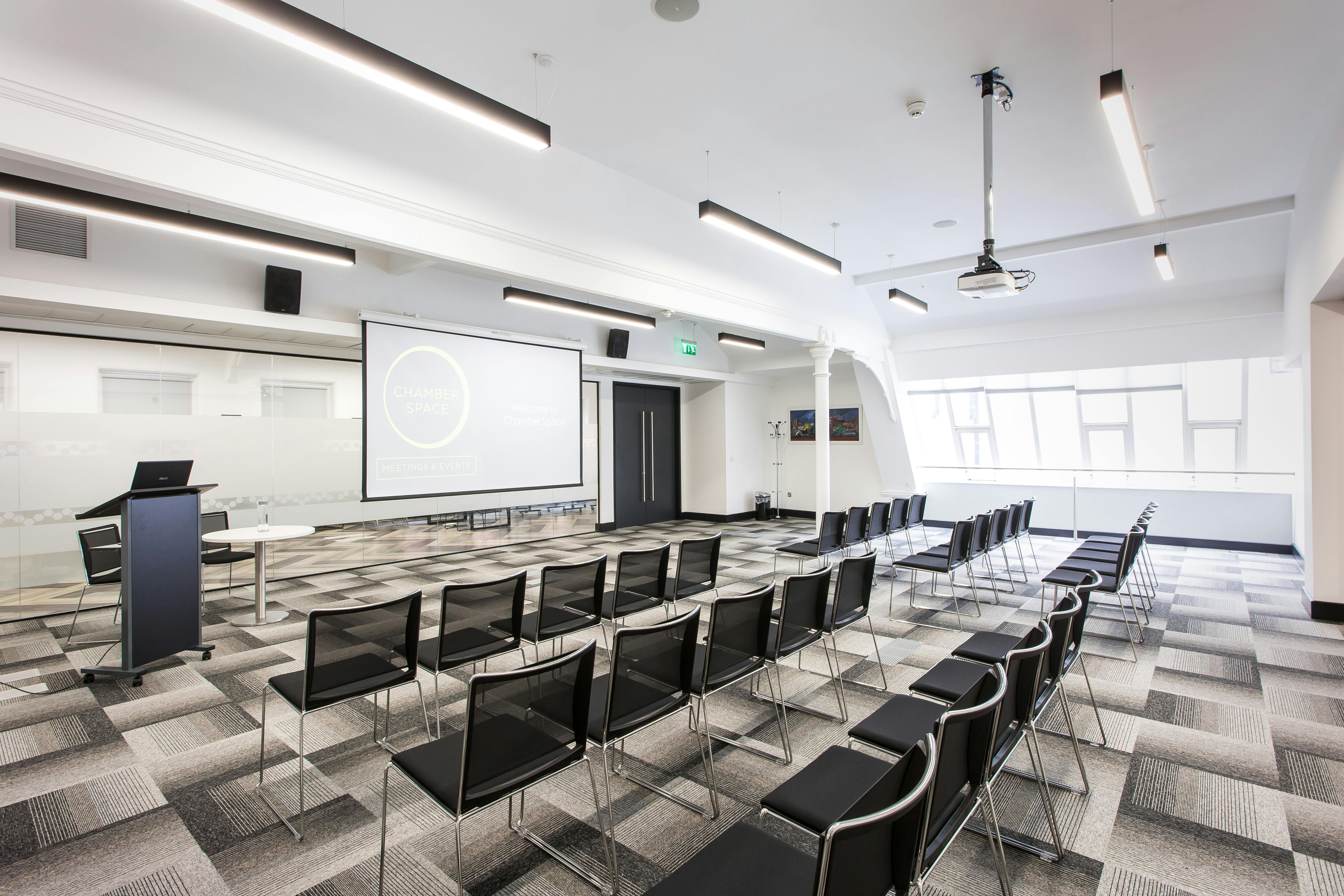 Modern meeting space with black chairs and large screen for corporate events and workshops.