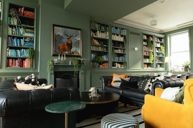 Stylish lounge in The Library, featuring green walls and cozy seating for networking events.