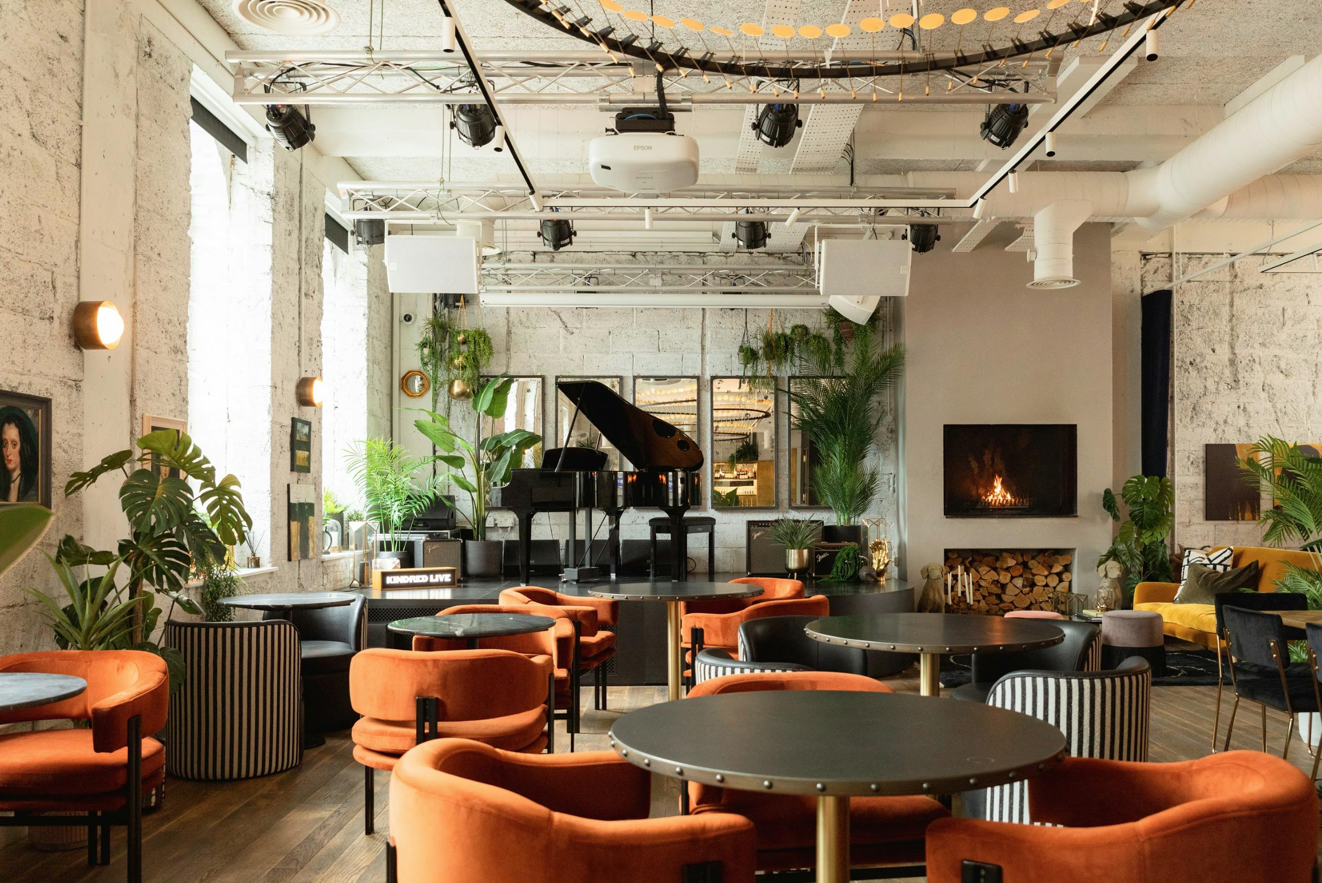 Stylish event space in Kindred with orange seating and grand piano for networking events.