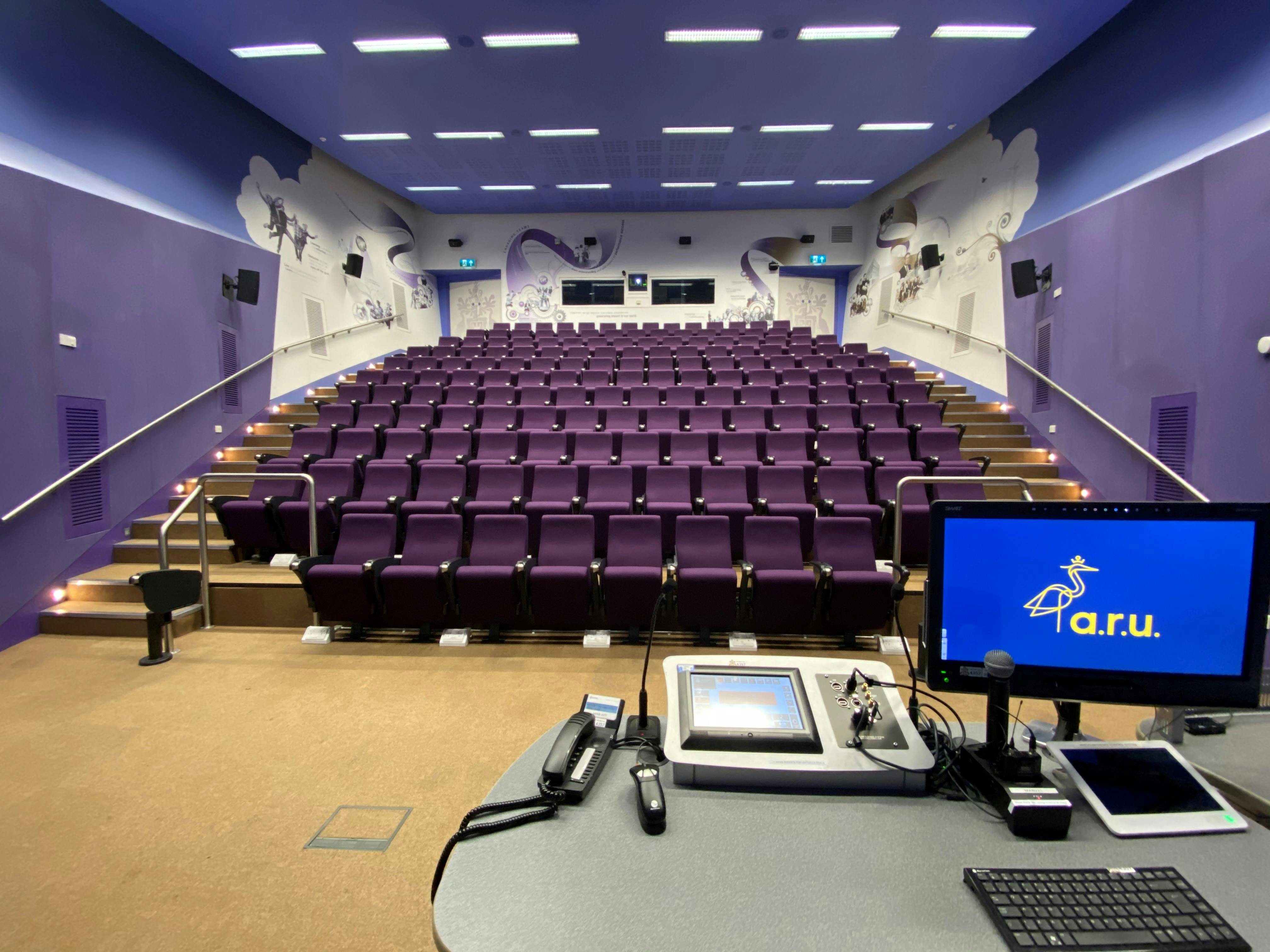 Modern auditorium with tiered seating in vibrant purple for events and meetings.