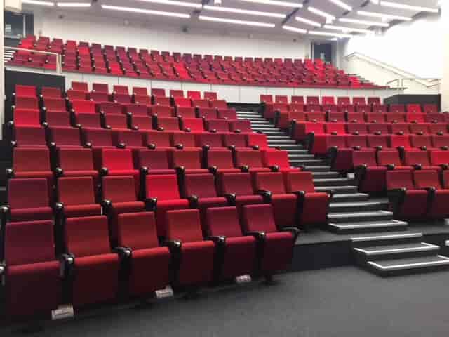Modern auditorium with tiered red seating for conferences and presentations in Cambridge.