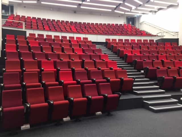 Modern auditorium with tiered red seating for conferences and presentations in Cambridge.