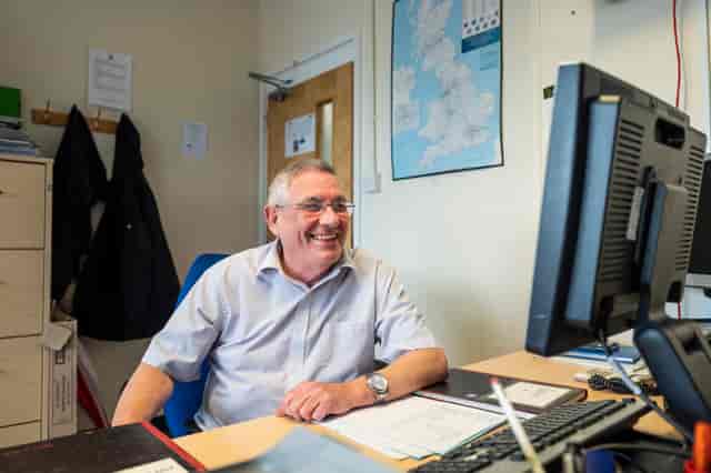 Meeting room at Liverpool Film Studios with a smiling event planner at his computer.