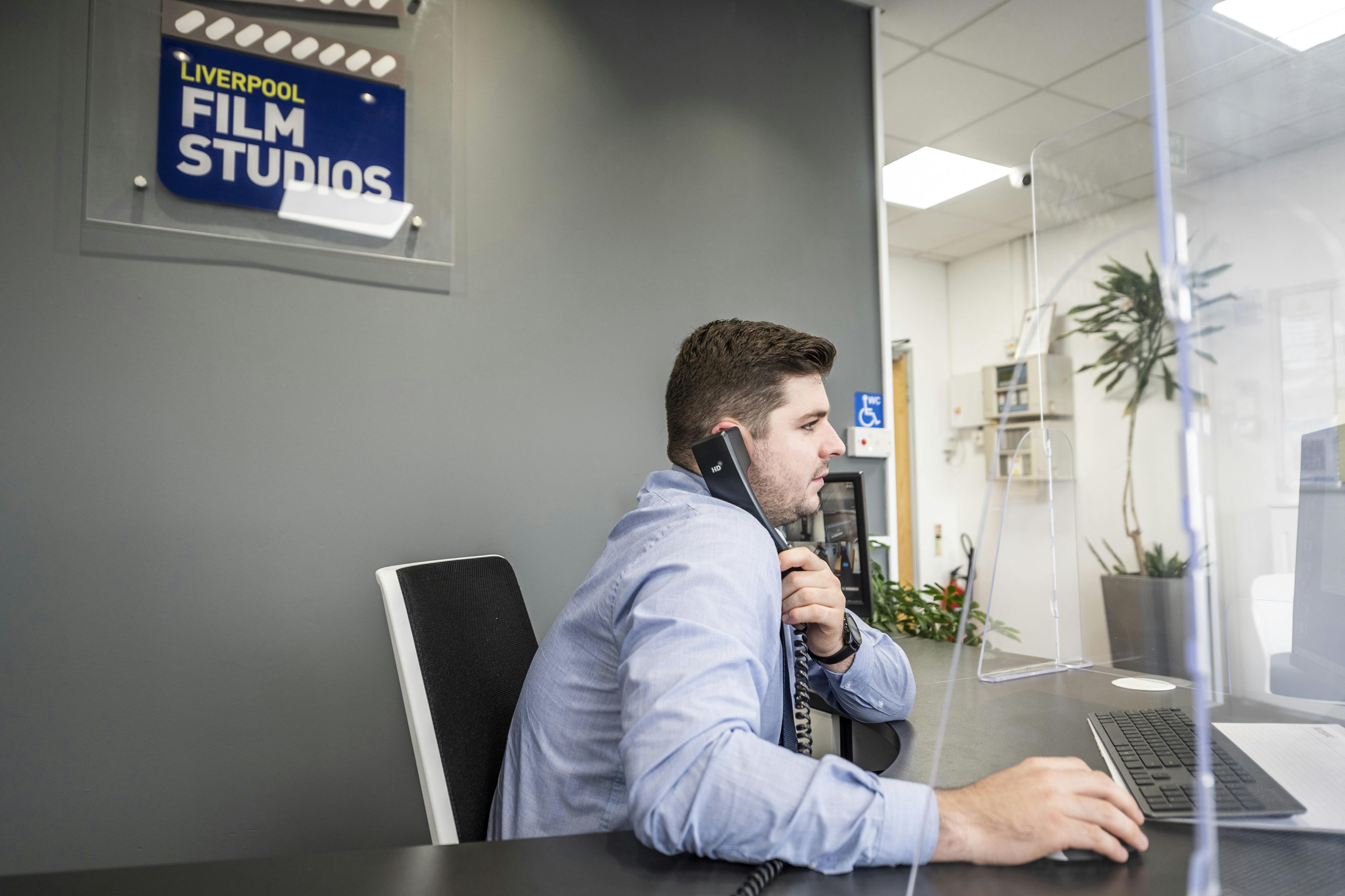 Professional at reception desk in Liverpool Film Studios, ideal for film events and meetings.