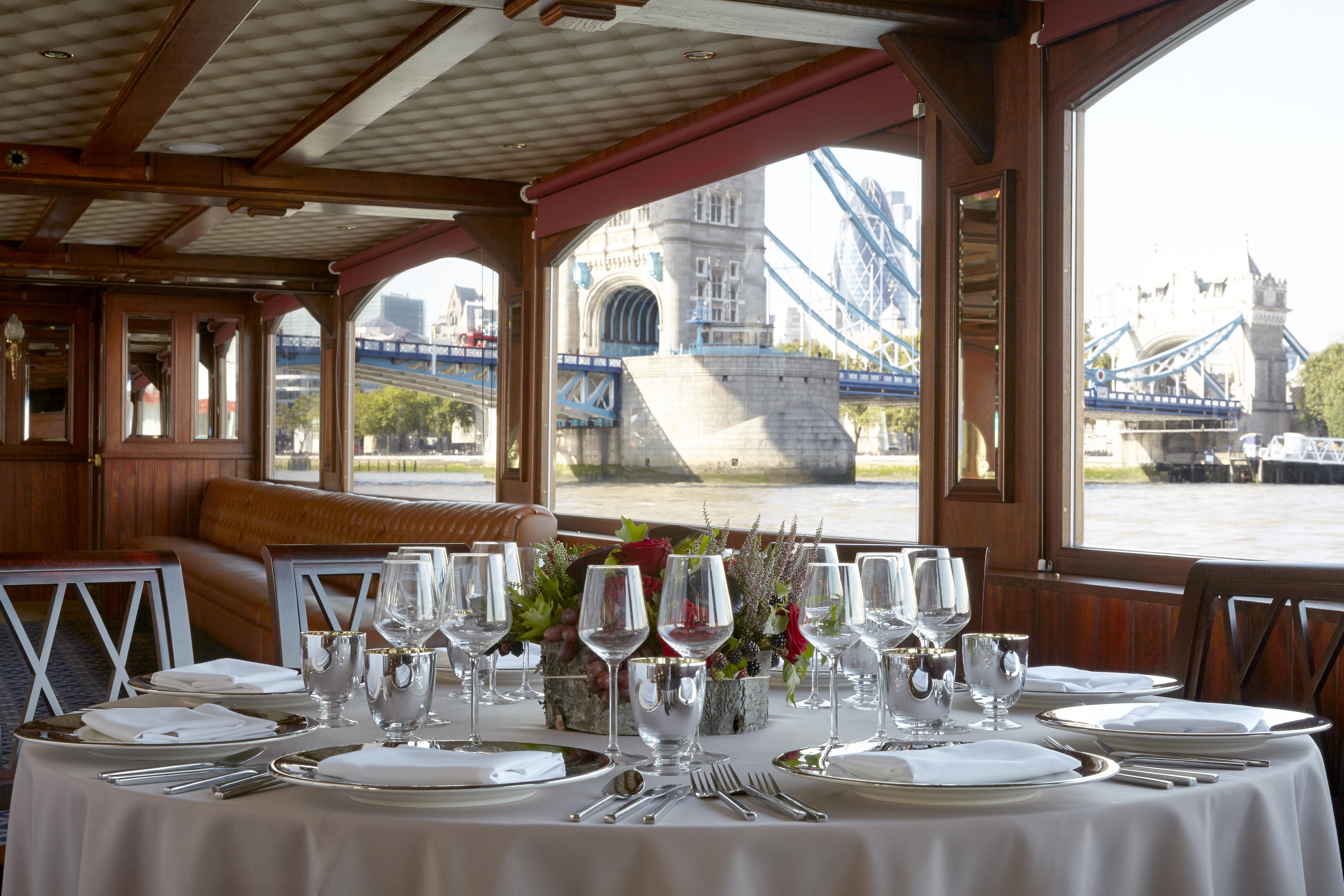 Elegant dining table on a boat with Tower Bridge view, perfect for upscale events. - Banner