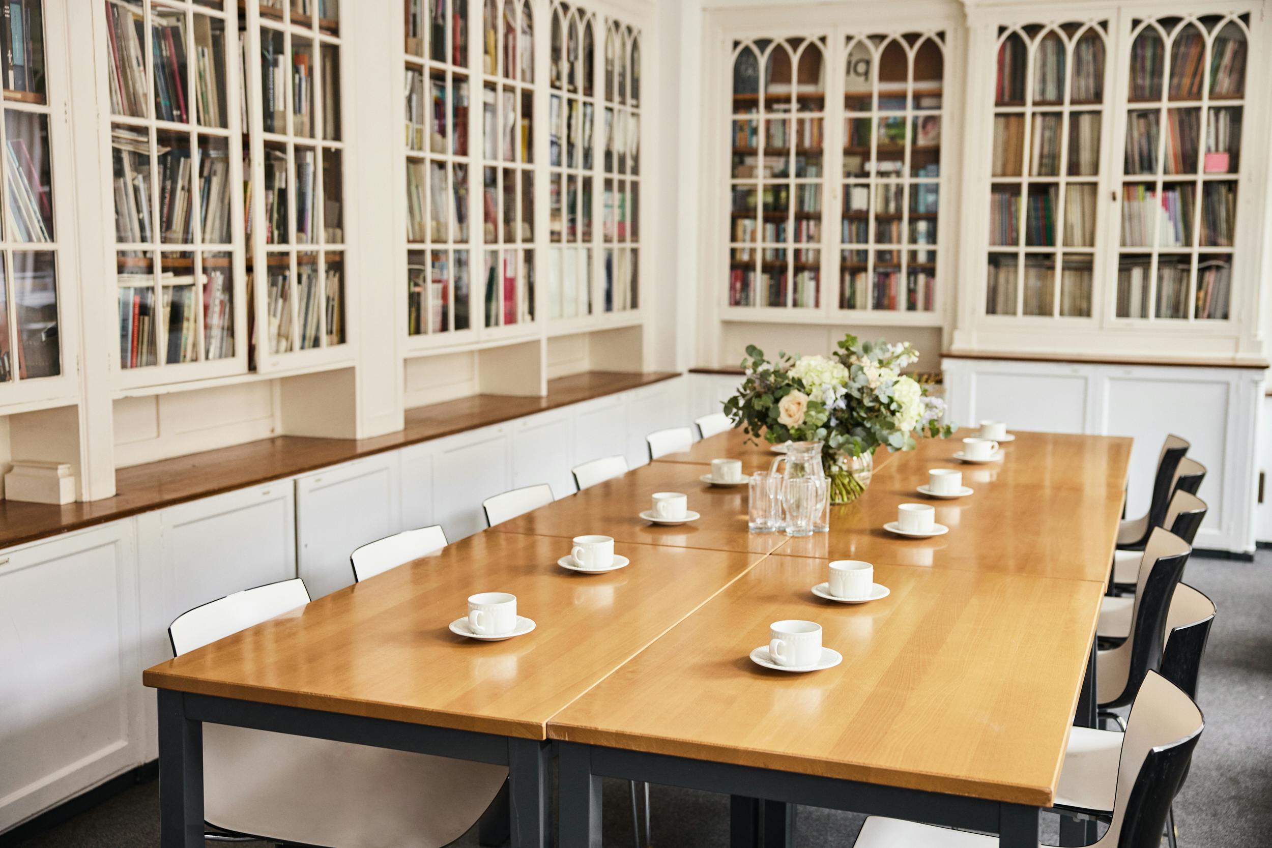 Library meeting room with wooden table, floral centerpiece for workshops and executive meetings.