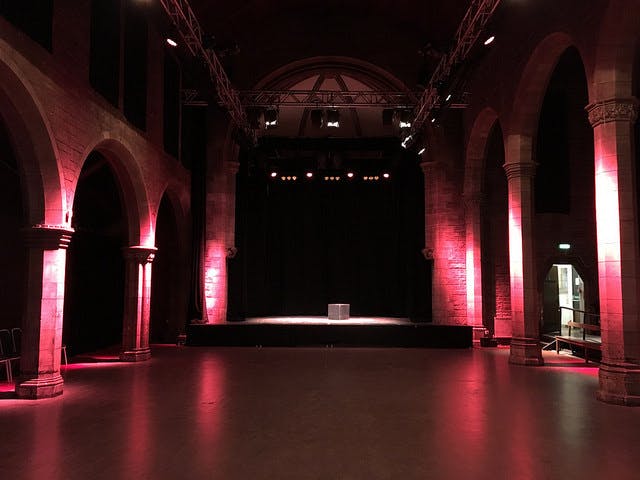 Roxy Central event space with raised stage and dramatic red lighting for performances.