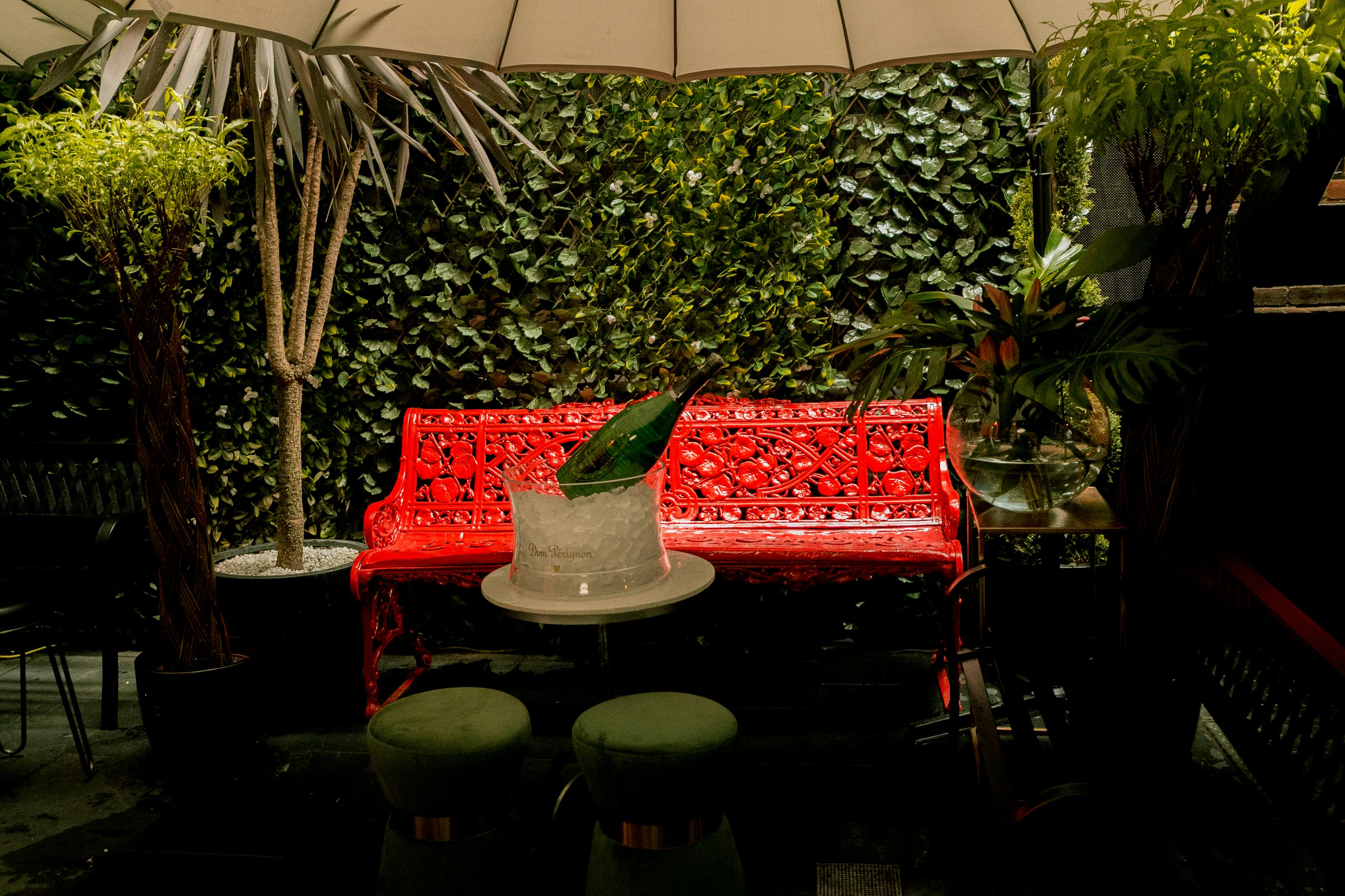 Vibrant Maddox Club Mayfair garden with red bench, ideal for networking events.