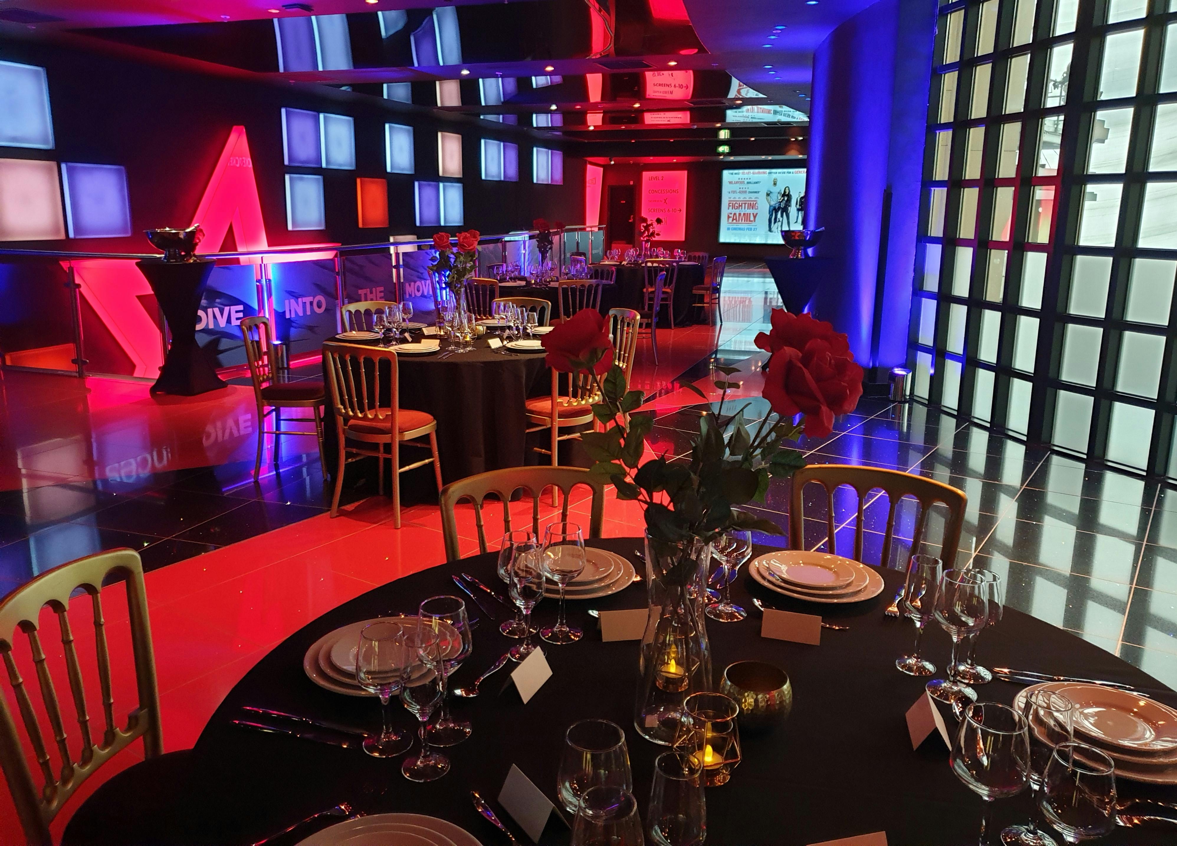 Elegant event space in Cineworld O2 Greenwich with round tables and red roses.