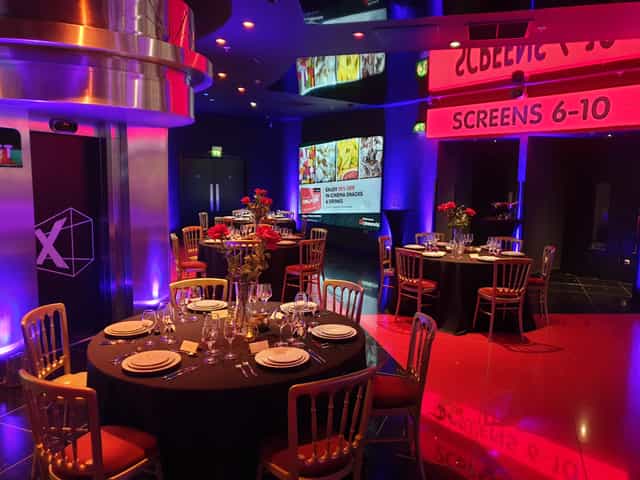 Upper Foyer at Cineworld O2 Greenwich, elegant dinner setup with black tables and gold chairs.