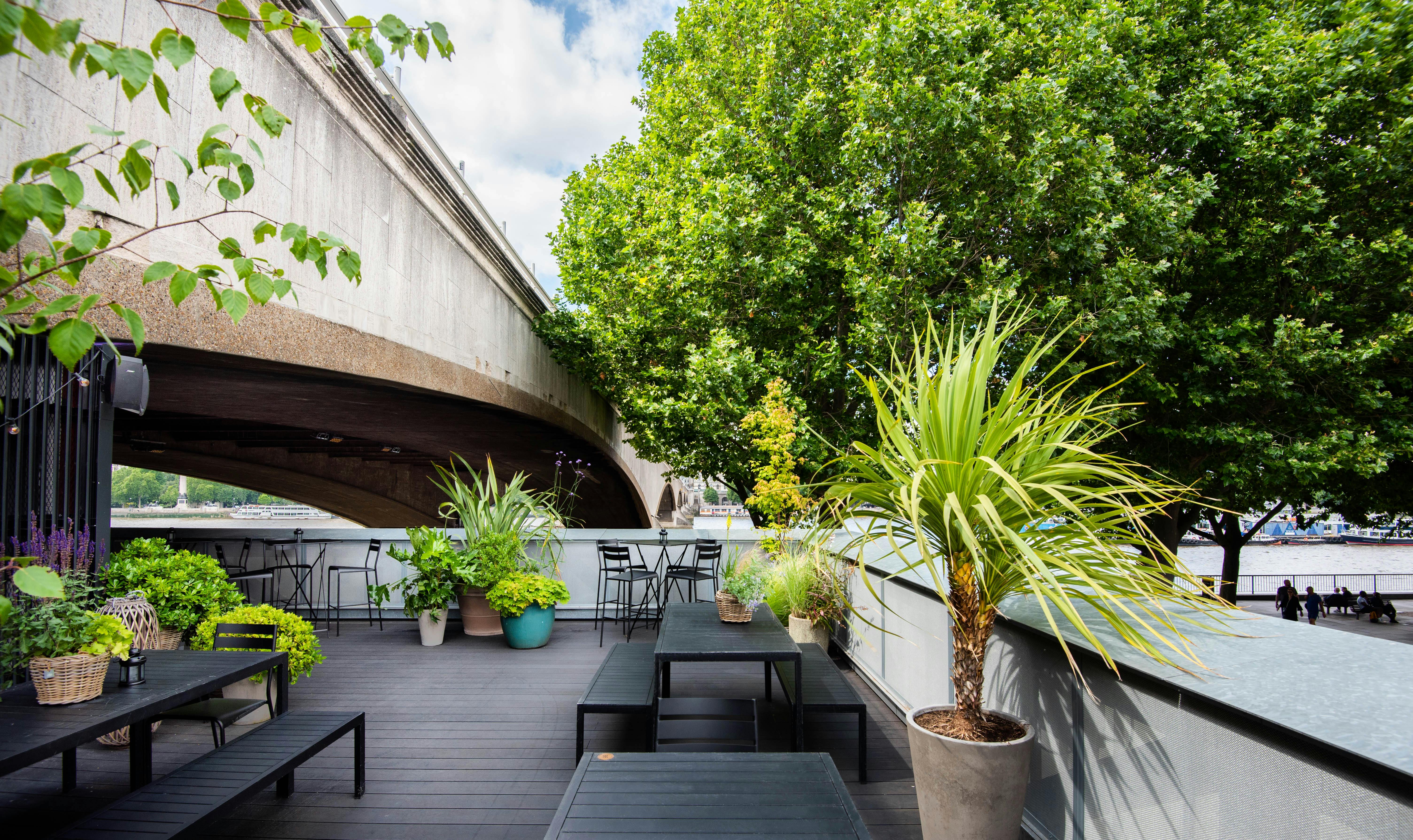 Stylish outdoor event space with modern furniture and greenery at Balcony Bar, Riverfront Terrace.