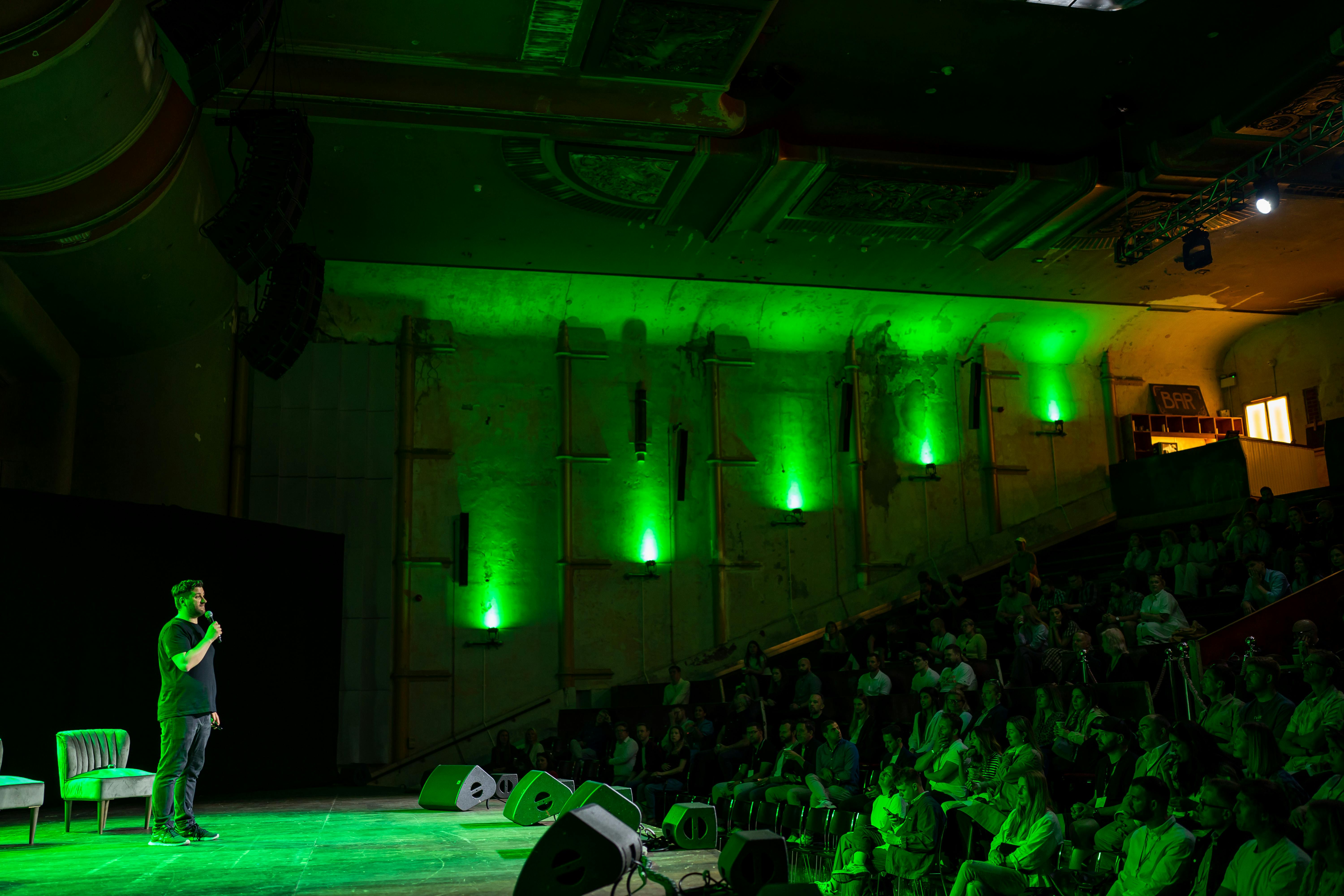 Dynamic speaker engaging audience in well-lit EartH theatre, showcasing effective event design.