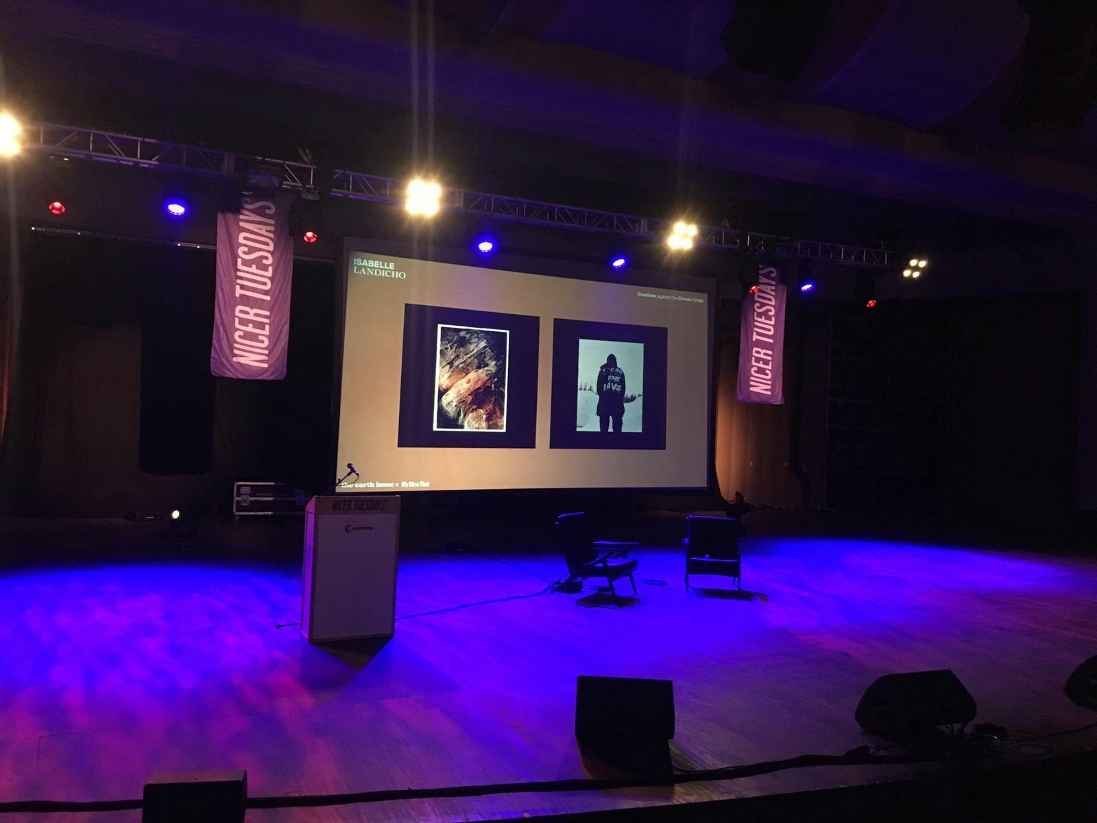 Theatre in EartH event space with stage, screens for presentations and discussions.