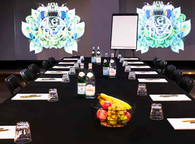 Meeting setup at Le Club, black linen table with notepads and vibrant graphics.