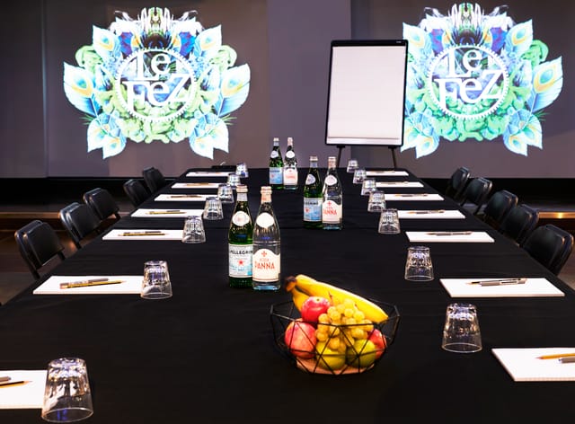 Meeting setup at Le Club, black linen table with notepads and vibrant graphics.