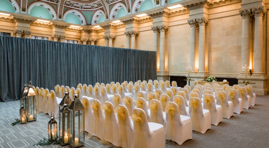 Elegant Sansovino Hall with white chairs and yellow sashes for weddings and events.